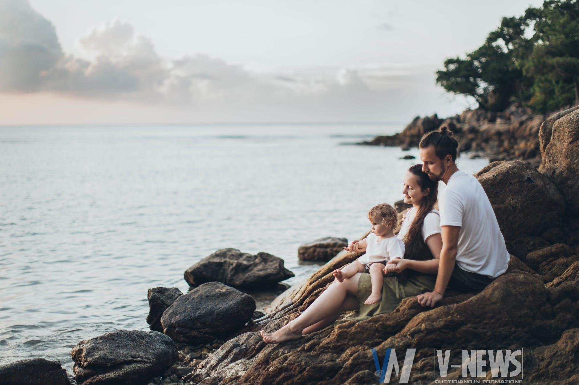 man and woman sitting on rock near seashore